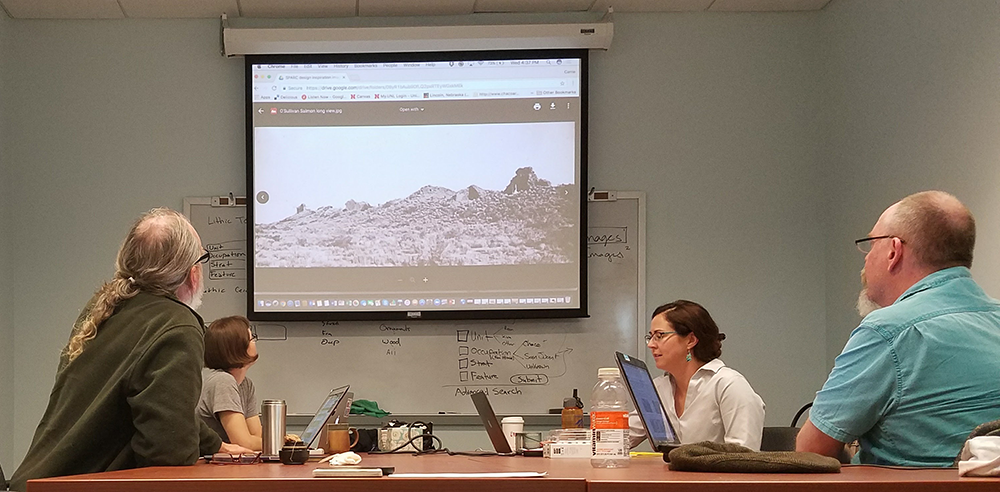 several people around conference table, looking at projection